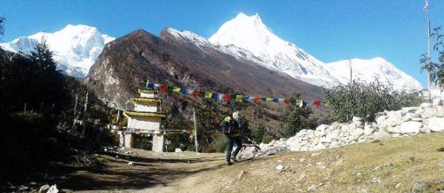 Larke Peak summit with climber and Himalayan mountain panorama during Manaslu Circuit Trek, Nepal.