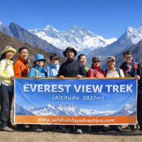 Group of eleven trekkers standing together outdoors, smiling at the camera while holding a white banner that reads ‘Everest View Trek (Altitude: 3,837m)’ with a clean design and no background graphics.