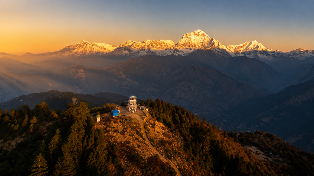 Poon Hill sunrise over the Annapurna mountain range, with golden morning rays illuminating the Himalayan peaks.