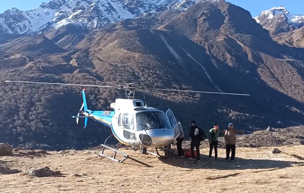 Scenic view of the Manaslu Circuit trek in Nepal, showing rugged Himalayan peaks, a winding trail, and a helicopter flying over the mountains for the helicopter return option.