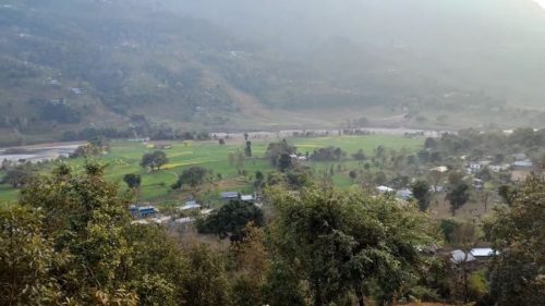 Beautiful rural landscape of Sukaura Village with mountains, greenery, and a glimpse of local village life.